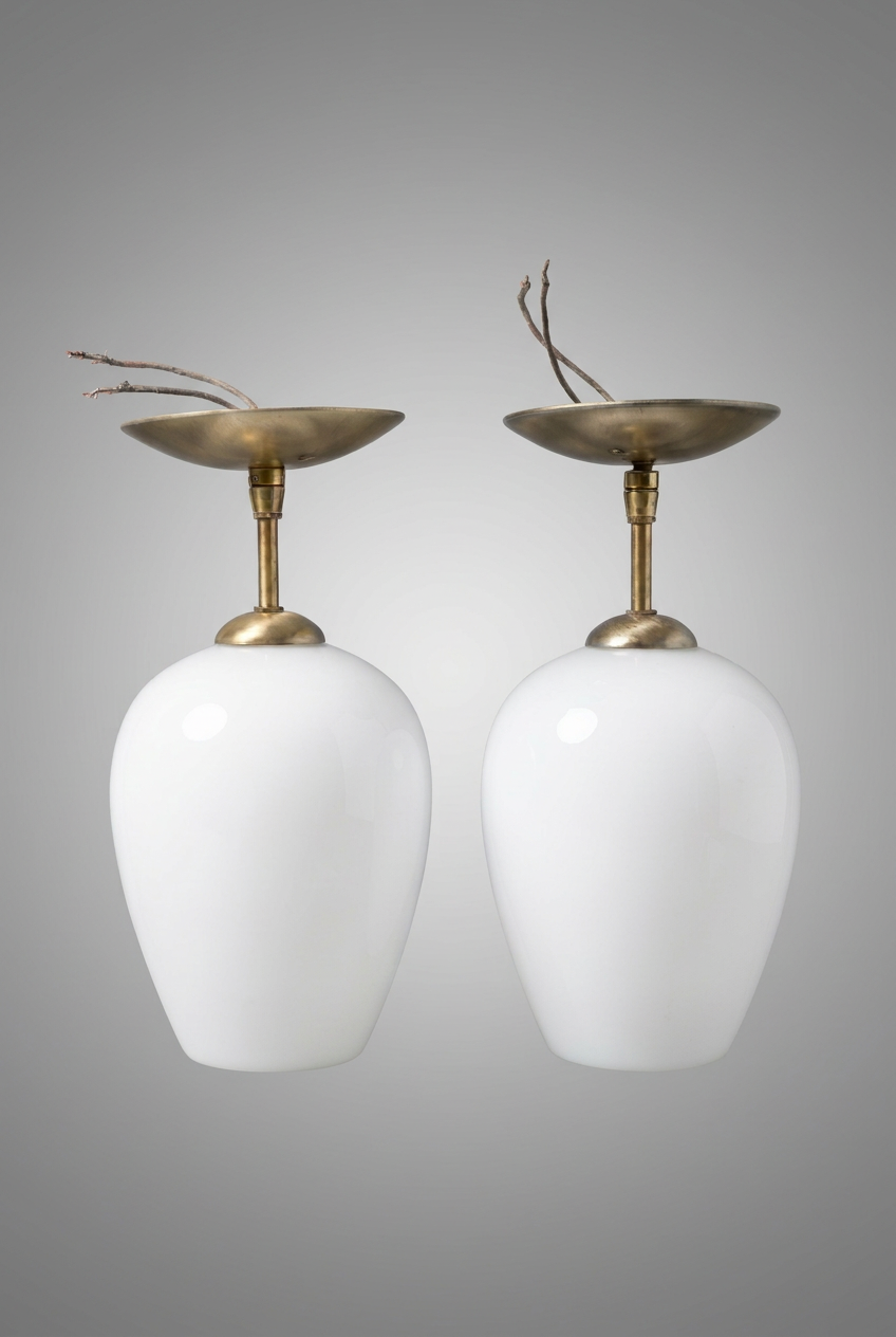 A pair of vintage mid-century modern table lamps with glossy white glass shades polished brass stems and brass lacquered canopies.