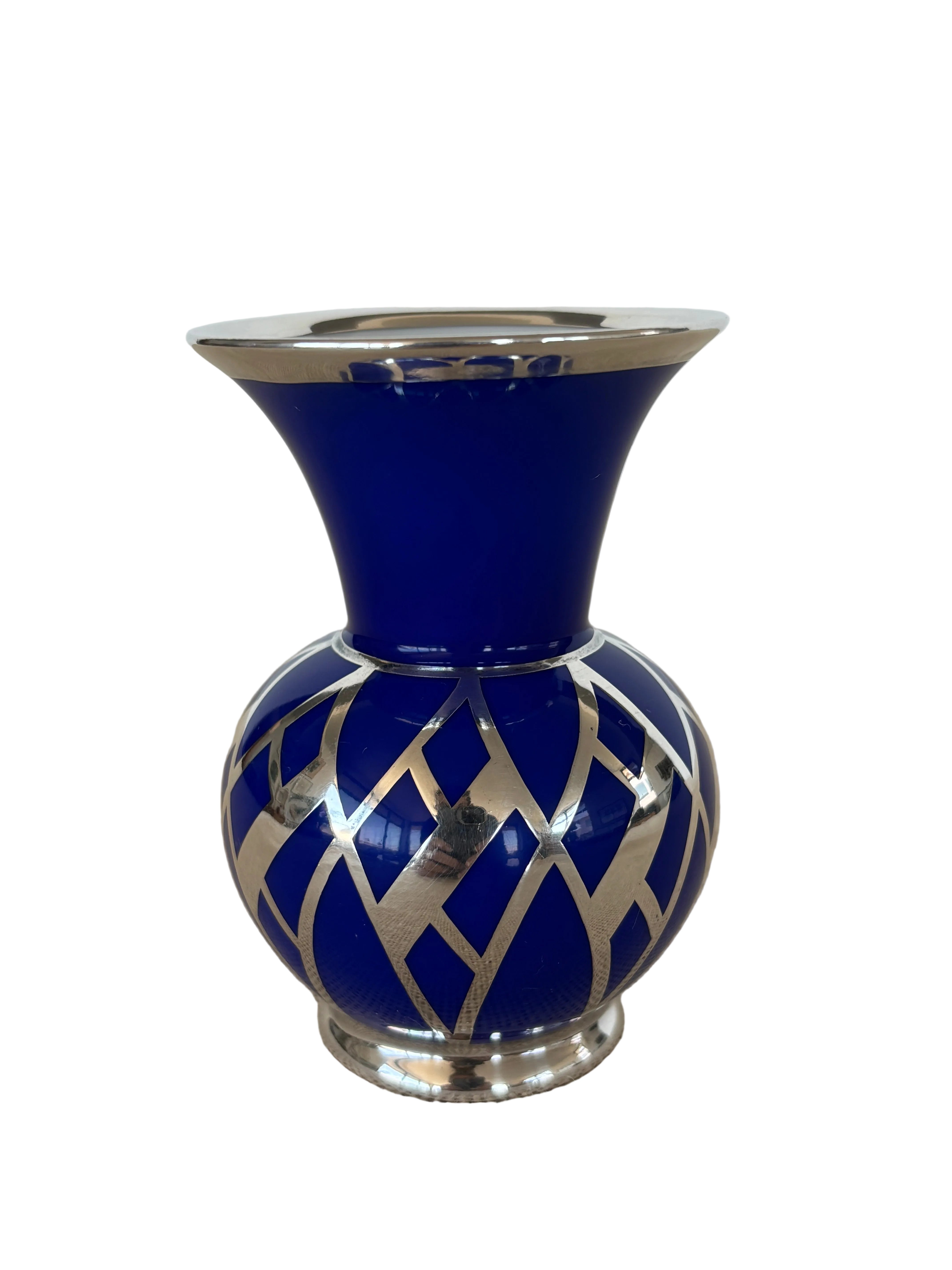 A small cobalt blue ceramic vase with a flared neck and a geometric silver lattice pattern around the bottom.