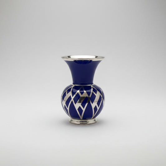 A small cobalt blue ceramic vase with a flared neck and a geometric silver lattice pattern around the bottom.