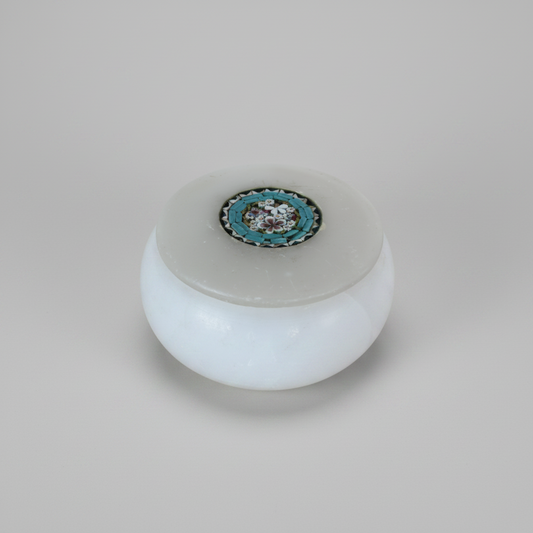 A small round white marble jar with a lid, featuring a decorative circular micro mosaic inlay on top with red and white floral details and turquoise background.