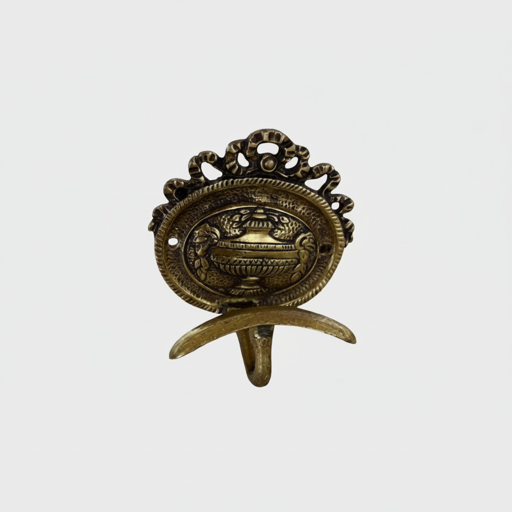 A baroque style brass coat hook with a center back urn motf and top bow detail.
